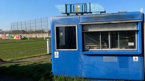 Cameron Weldon/BBC The old blue Tamar Bridge booth that had been at the far end of Saltash United's ground which was donated to the club about 20 years ago. It's got a door and a glass sliding window.