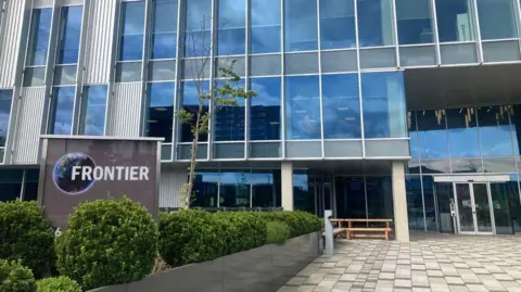 Mousumi Bakshi/BBC Image shows huge, multi-level glass fronted building with the company's name - Frontier - written in large lettering outside