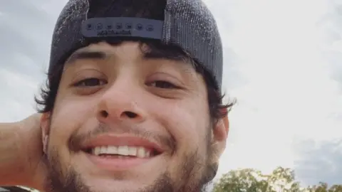 Go Fund Me Julian Ryan wears a baseball cap and smiles at the camera.