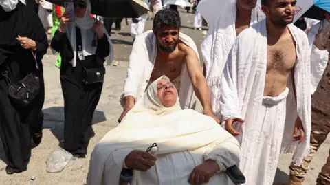 Getty Images A woman affected by the scorching heat is pushed on a wheelchair as Muslim pilgrims arrive to perform the symbolic 'stoning of the devil' ritual as part of the hajj pilgrimage in Mina, near Saudi Arabia's holy city of Mecca, on June 16, 202