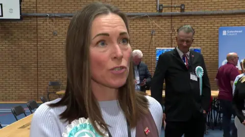 Fiona Pearce at the election count. She has shoulder-length brown hair and is wearing a Reform rosette.
