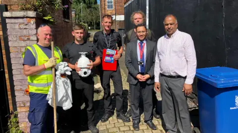 BBC Launch of Love Your Street campaign. Six men look at the camera, including one holding a stick and bags and wearing gloves. 