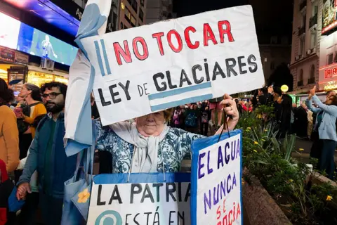 Getty Images An eldery lady holds a sign which says in Spanish 'Don't touch the glacier law'