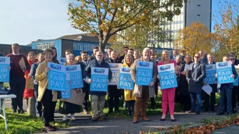 BBC a line of people holding signs for NAHT, a headteachers' union