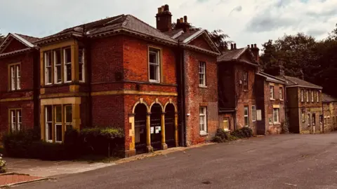 Andy Kershaw A large red brick mansion with several entrances and grand windows