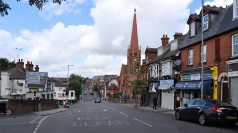 Victoria Street. There is a road with shops on either side, and a red brick church on the right.