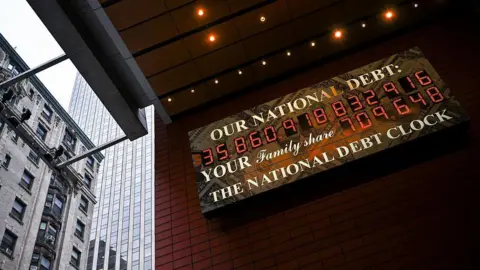 A screen displaying the US national debt is seen in the Manhattan borough of New York City on April 11, 2025. 