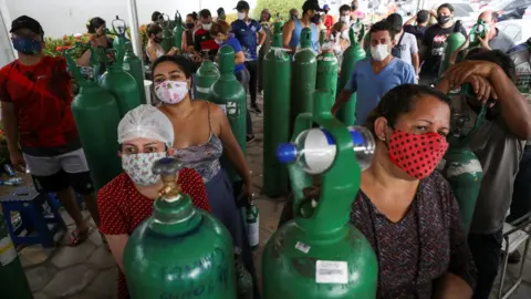 Reuters Relatives of patients hospitalised or receiving healthcare at home gather to buy oxygen and fill cylinders at a private company in Manaus