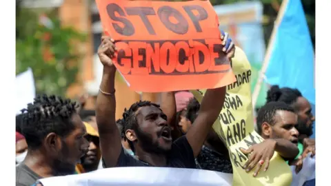 AFP Protesters holding a banner that says "stop genocide"