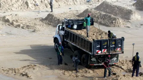 Getty Images Men load a truck with sea sand on a beach in Senegal