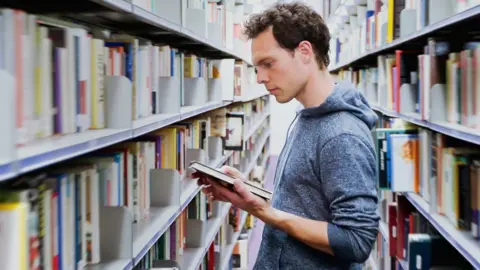 Getty Images A student in a library surrounded by bookshelves