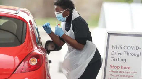 Getty Images A nurse takes a swab at a Covid-19 Drive-Through testing station for NHS staff on March 30, 2020 in Chessington, United Kingdom