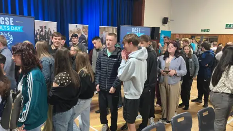 Queue of young people in school hall waiting for the results