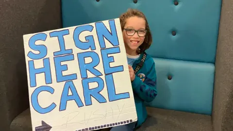 BBC/Dan Sambell Leo holds his sign with Carl Rushworth's signature at the bottom.