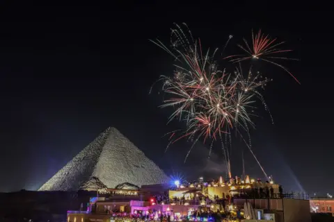 Mohamed Elshahed/Anadolu via Getty Images Kembang api menerangi langit malam untuk menyambut tahun baru di piramida di Giza, Mesir - 1 Januari 2025. 