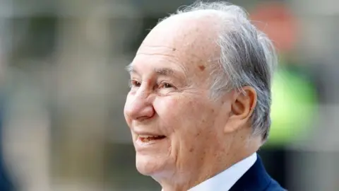 Max Mumby/Indigo/Getty Images An elderly man with grey hair and freckles is looking into the distance and smiling. 