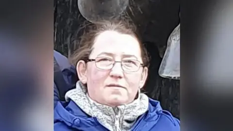 A head and shoulders picture of Marta Bednarcyzk, who has a blue coat and a fleece on. She has glasses and brown or ginger hair tied back, looking towards the camera.