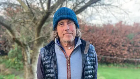 A man in a blue hat. He has long hair.