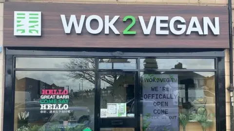 Wok2Vegan The outside of a takeaway, with a large brown sign saying 'Wok2Vegan' on it.