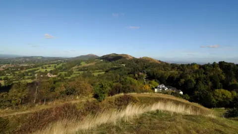 BBC A landscape view from atop a hill. Rolling hills covered in trees can be seen all the way to the skyline