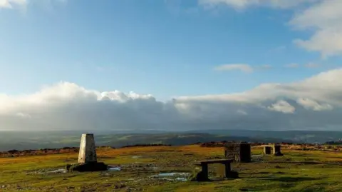 Moorland with a white concrete Triangulation Point in the foreground.