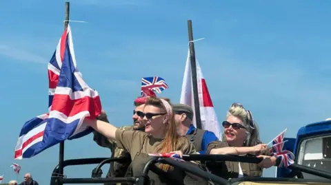 BBC Four people dressed in khaki wave flags including a union flag.