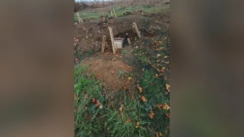 Warsop Wildlife Rescue Team Mobile phone image of two low mounds of grassy earth, which have mesh over them and in the centre of one is a small wooden door.