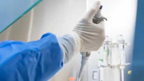 A gloved hand holding science equiptment