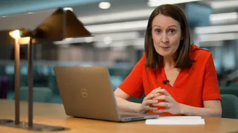 Vanessa Clarke sat at an office desk with a laptop