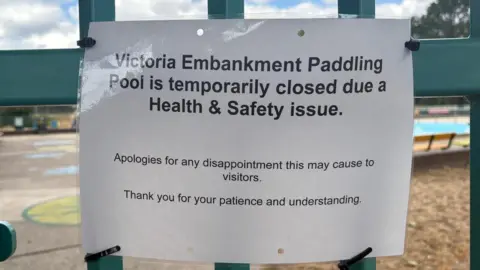 A sign has been tied to the entry to the pool explaining to visitors that it has been closed due to a health and safety issue and apologising for any disappointment. 