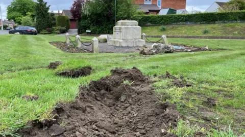 Lee Agnew/BBC The damaged memorial, with turfed up grass in the foreground