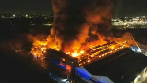 An aerial image of a large building on fire with glowing orange flames