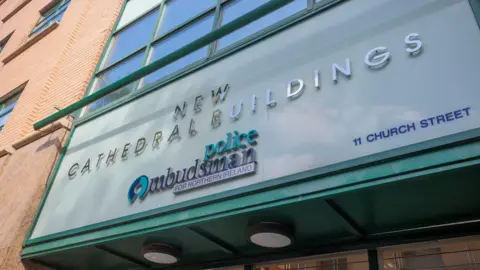 PA Media Above the entrance to the police ombudsman's office a sign reads 'NEW CATHEDRAL BUILDINGS: police Ombudsman FOR NORTHERN IRELAND'. The lettering is silver, navy and green, and is set against a background of lighter, pastel green. 
