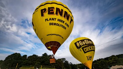 Ben Birchall/PA Wire Two yellow hot air balloons