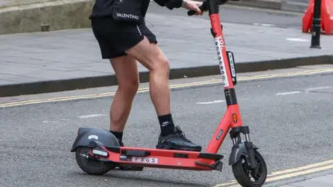 Getty Images A man riding a Voi scooter