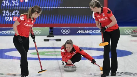 AFP via Getty Images Canada's Rachel Homan (centre) delivers the stone during the curling women's round robin between Canada and Switzerland on 14 February 2026.