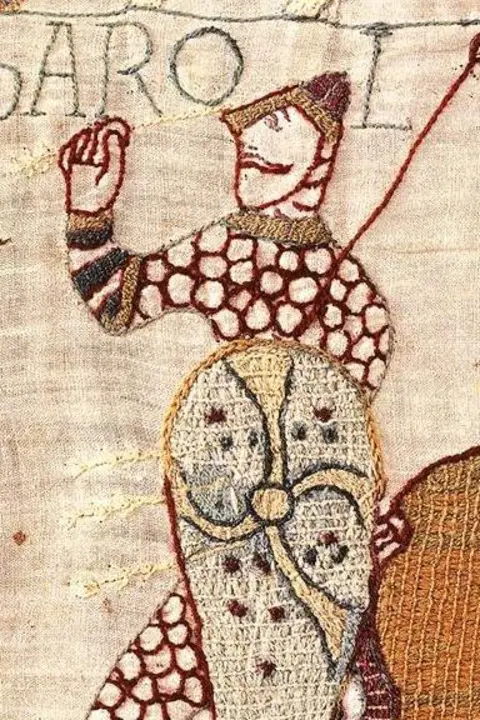 Bayeux Museum A close crop shows Harold depicted as being shot with an arrow next to a horse, with writing reading 'Harold rex' with fabric detail.