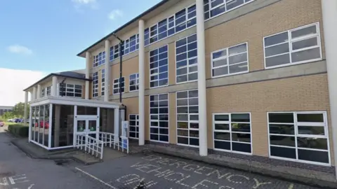 A three-storey building of brown bricks with white-framed windows