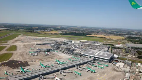 Getty Images An aerial photograph of Dublin Airport on a bright day. Showing multiple Aer Lingus planes parked at stands outside the airport building.