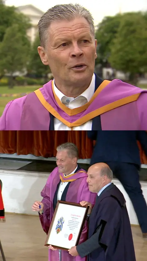 Man stood in purple gown at ceremony.
