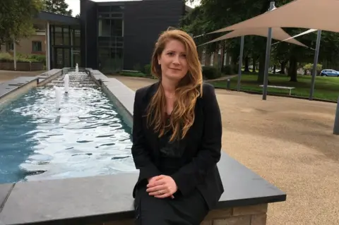 Dr Koshka Duff sitting next to a fountain at the University of Nottingham