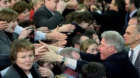 Getty Images/ PAUL J .RICHARDS US President Bill Clinton shakes hands with local residents after addressing the people of Northern Ireland in the Odyssey Arena 13 December 2000 in Belfast. President Clinton is visiting Ireland for the third time and hopes to further the peace process in the region