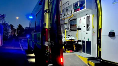 An ambulance with the back doors open showing medical equipment. 