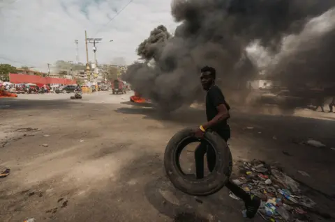 Marcin Kornacki A man runs with a tyre in Port-au-Prince