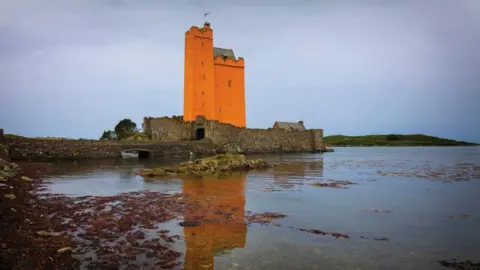 Getty Images An orange castle by water. 