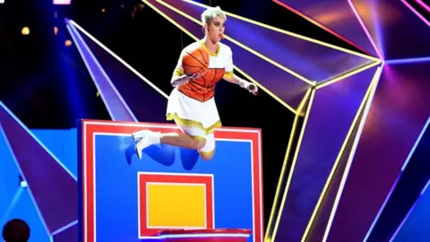 Getty Images Katy Perry suspended over a basketball hoop mid performance