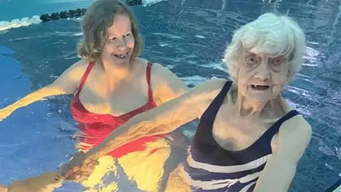 BBC Edd Smith holding hands with Iris Moreton in a swimming pool.