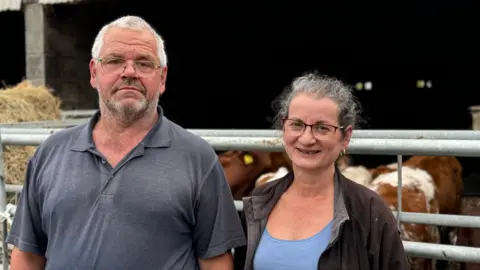 BBC Farmer couple stood in front of their herd