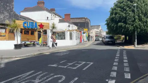 BBC Gibbon Lane in Plymouth. There is a venue called 'CUBA' on the left of the image and cars parked along a street.
