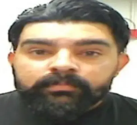 O Departamento de Segurança Interna é uma vaga caneca de Harginder Singh, que tem cabelos pretos e barba preta e bigode